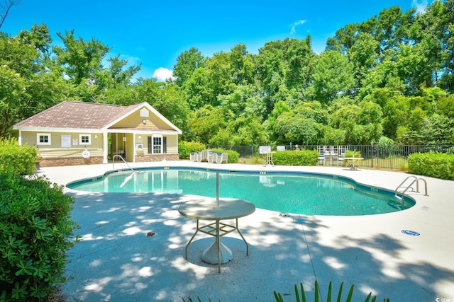 pool with an outbuilding, a patio area, fence, and an exterior structure