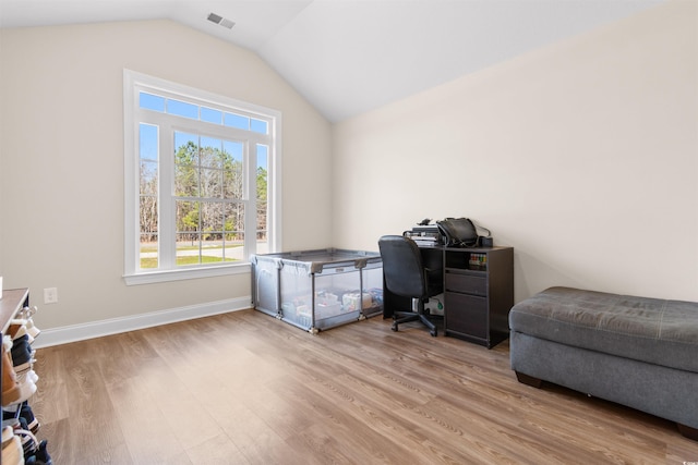 office featuring vaulted ceiling, light wood-type flooring, visible vents, and baseboards