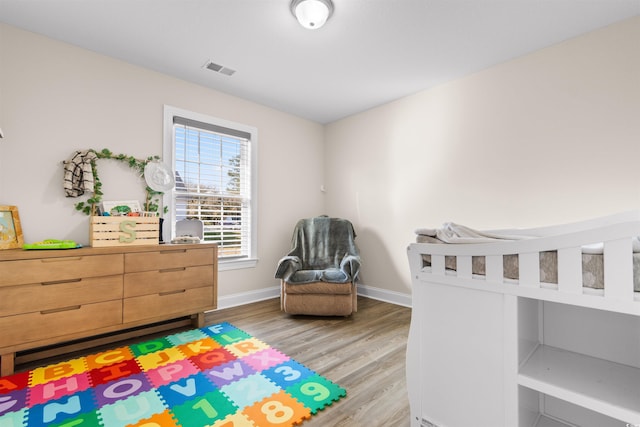 bedroom with light wood-type flooring, visible vents, and baseboards