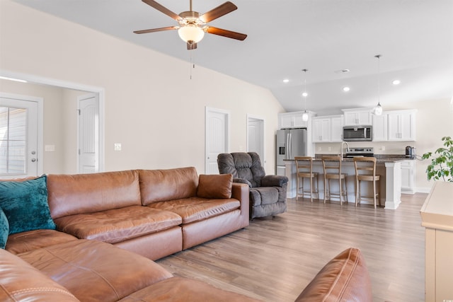 living room with vaulted ceiling, ceiling fan, light wood-style flooring, and recessed lighting