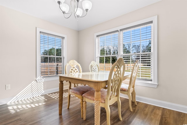 dining space with dark wood-style flooring, a notable chandelier, and baseboards