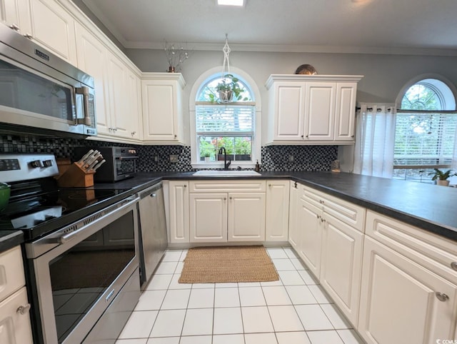 kitchen with light tile patterned floors, backsplash, appliances with stainless steel finishes, ornamental molding, and a sink