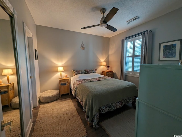 bedroom featuring a textured ceiling, visible vents, and a ceiling fan