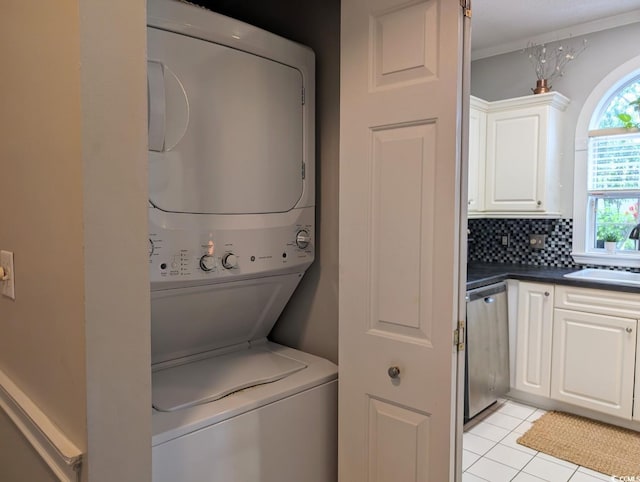 washroom featuring stacked washer / drying machine, laundry area, a sink, and light tile patterned floors