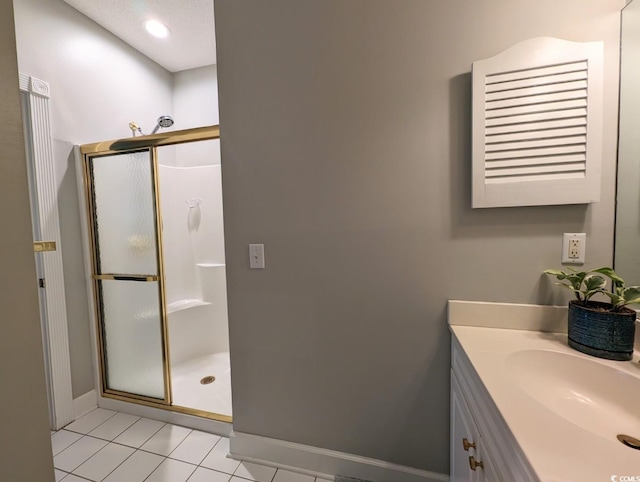 bathroom with baseboards, a stall shower, vanity, and tile patterned floors