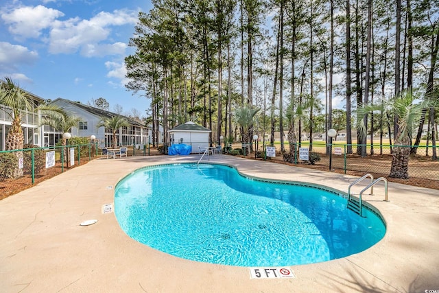 community pool featuring fence, an outbuilding, and a patio