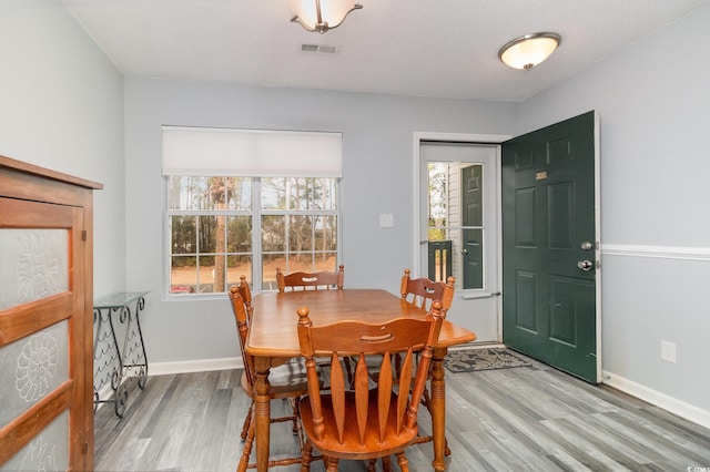 dining space with light wood-style floors, visible vents, and baseboards
