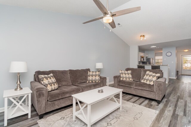 living room with light wood-style floors, visible vents, vaulted ceiling, and baseboards
