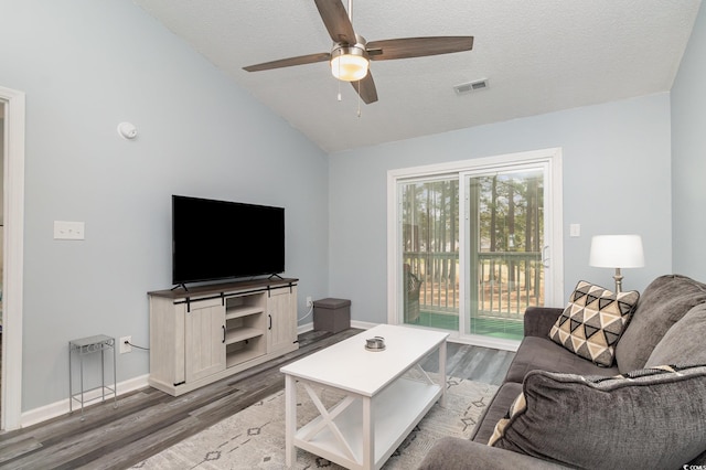 living area with lofted ceiling, a textured ceiling, wood finished floors, visible vents, and baseboards