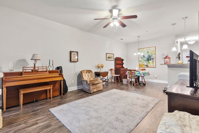 interior space featuring ceiling fan with notable chandelier, baseboards, and wood finished floors