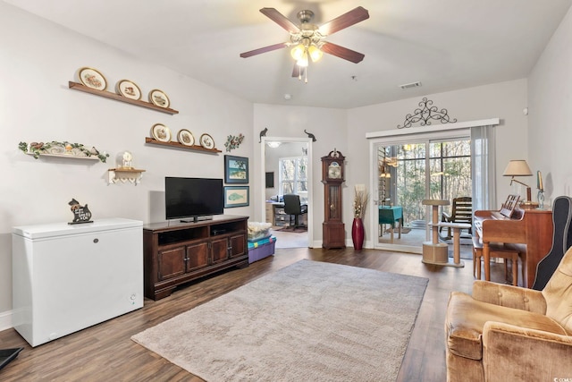 living area with baseboards, ceiling fan, visible vents, and wood finished floors