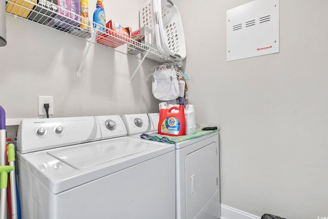 washroom with laundry area, separate washer and dryer, and baseboards