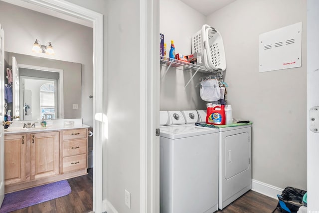 laundry area with laundry area, dark wood-type flooring, a sink, baseboards, and washer and clothes dryer