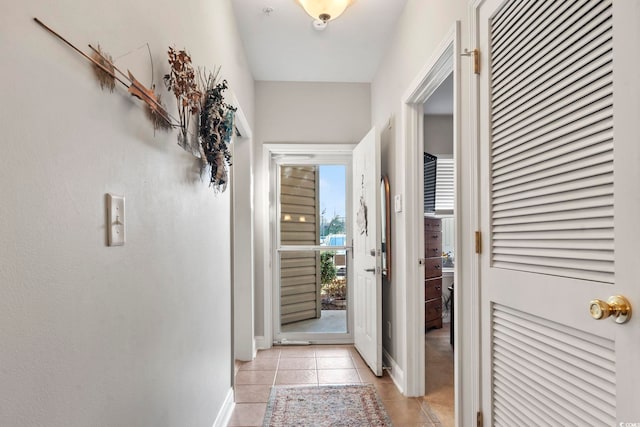 doorway with baseboards and light tile patterned flooring