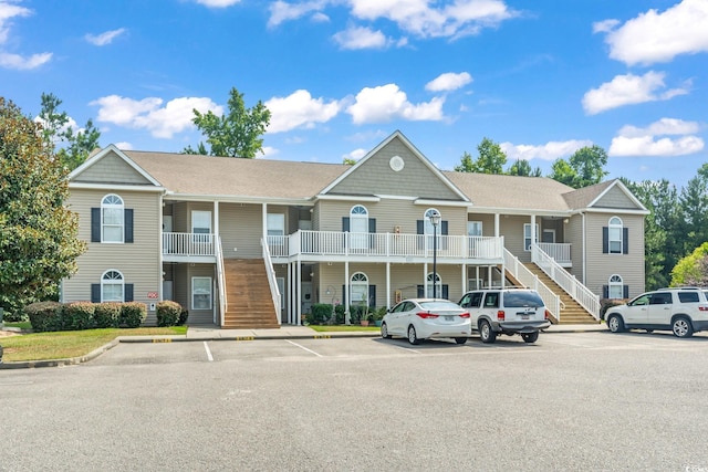 view of building exterior with stairs and uncovered parking