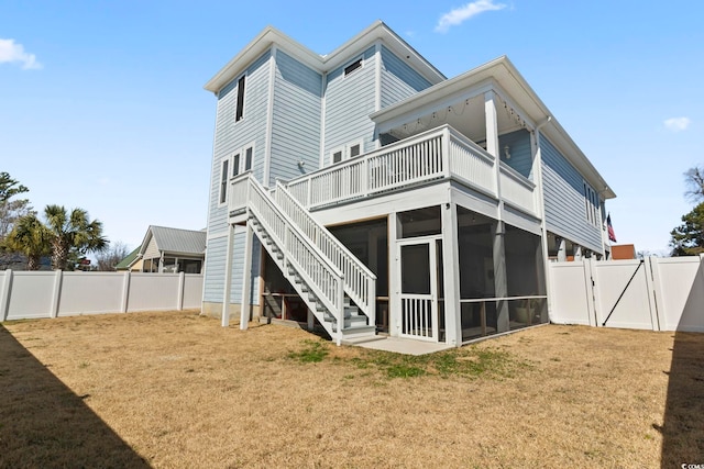 back of house featuring a fenced backyard, a sunroom, a yard, stairway, and a gate