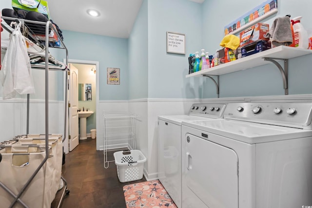 clothes washing area with a sink, laundry area, wainscoting, and washing machine and dryer