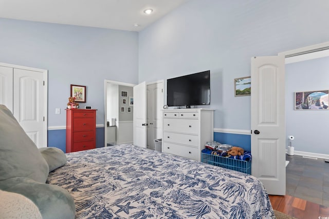 bedroom featuring baseboards, high vaulted ceiling, and wood finished floors