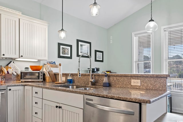 kitchen with a sink, dark stone countertops, dishwasher, and decorative light fixtures