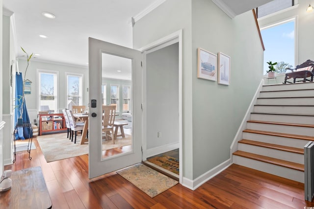 foyer entrance featuring recessed lighting, wood finished floors, baseboards, ornamental molding, and stairway