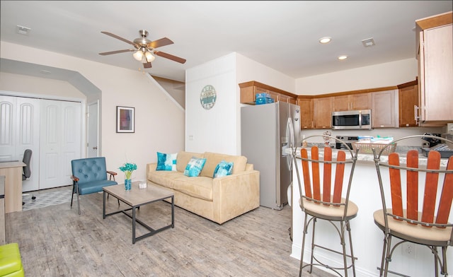 living room featuring light wood finished floors, visible vents, arched walkways, a ceiling fan, and recessed lighting