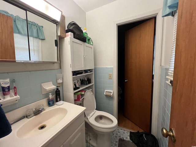 bathroom featuring toilet, vanity, tile walls, and wainscoting