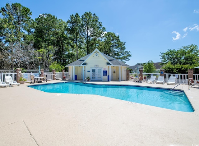 pool featuring a patio, an outdoor structure, and fence