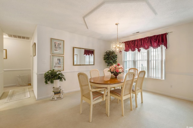 dining area featuring visible vents, a chandelier, a textured ceiling, and light colored carpet