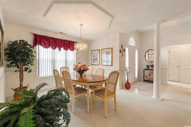 dining room featuring a textured ceiling, light carpet, visible vents, ornate columns, and an inviting chandelier