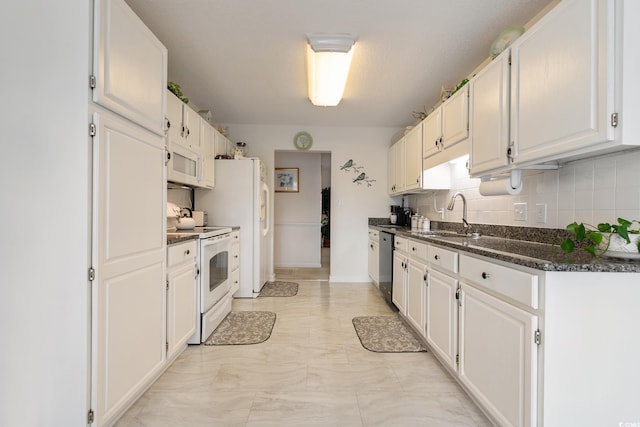 kitchen featuring white appliances, tasteful backsplash, white cabinets, and a sink