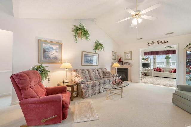 carpeted living room with ceiling fan, a fireplace, visible vents, and vaulted ceiling