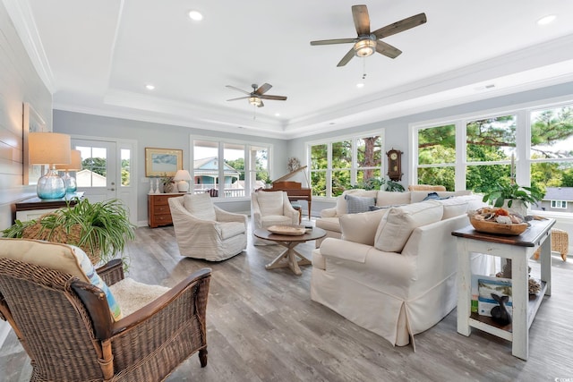 living area featuring light wood-style flooring, recessed lighting, visible vents, ornamental molding, and a raised ceiling