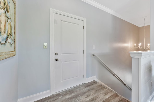 interior space with baseboards, ornamental molding, wood finished floors, and a notable chandelier