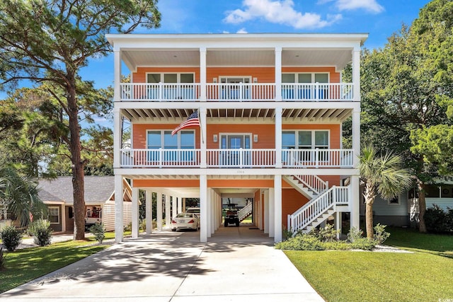 beach home featuring driveway, a porch, stairway, a front lawn, and a carport