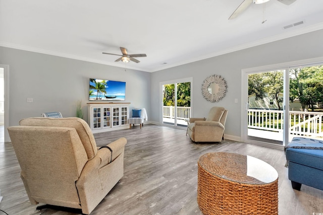 living room featuring ornamental molding, visible vents, ceiling fan, and baseboards