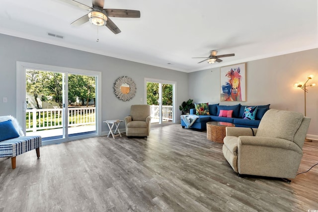 living room with visible vents, crown molding, baseboards, and wood finished floors