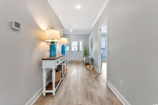 hall with ornamental molding, baseboards, and light wood finished floors