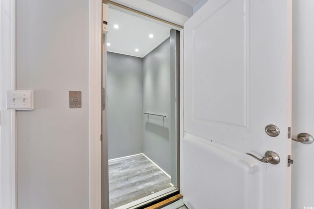 bathroom with elevator, wood finished floors, and recessed lighting