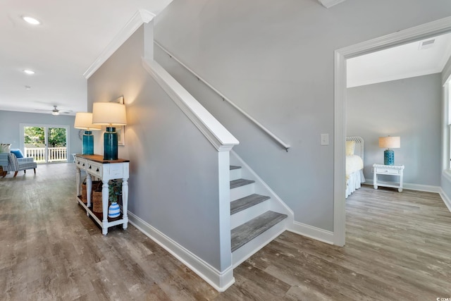 staircase with baseboards, crown molding, and wood finished floors