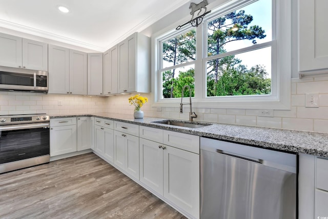 kitchen with tasteful backsplash, appliances with stainless steel finishes, a sink, and crown molding