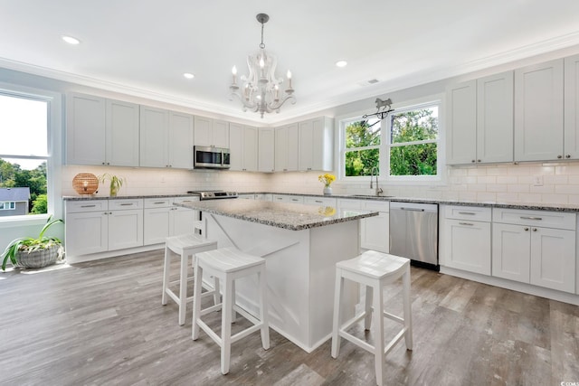 kitchen featuring stainless steel appliances, crown molding, backsplash, and a kitchen bar