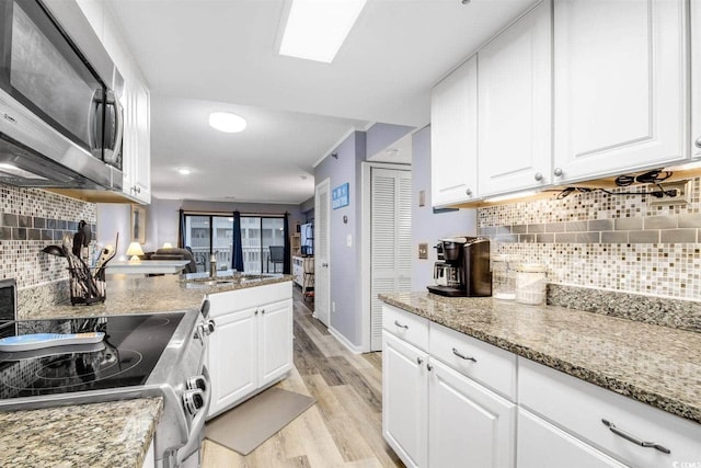 kitchen with white cabinetry, appliances with stainless steel finishes, light stone countertops, and light wood finished floors