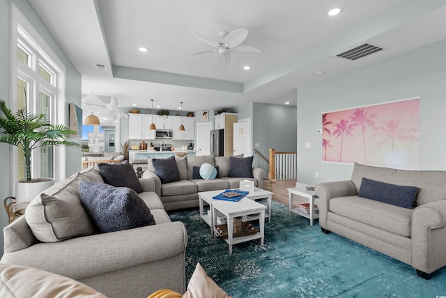 living room featuring a tray ceiling, recessed lighting, and visible vents