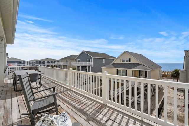 wooden deck featuring outdoor dining space, a residential view, and a water view