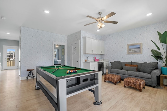 rec room with a sink, wine cooler, light wood-style floors, wallpapered walls, and indoor wet bar