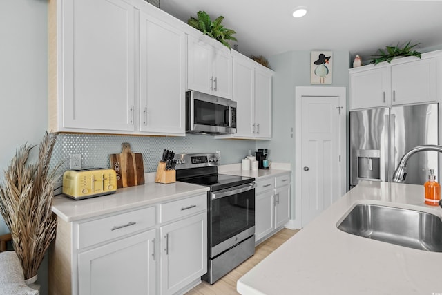 kitchen featuring decorative backsplash, light countertops, appliances with stainless steel finishes, and a sink