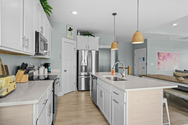 kitchen with a sink, a kitchen breakfast bar, backsplash, stainless steel appliances, and light wood finished floors