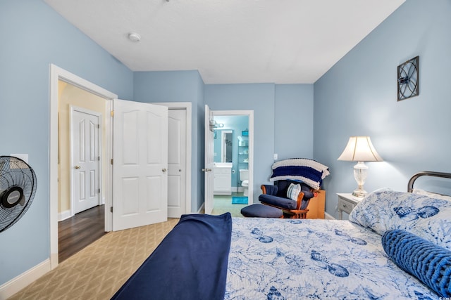 carpeted bedroom with ensuite bath and baseboards