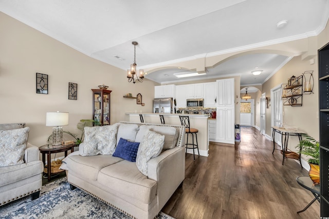 living room with arched walkways, a notable chandelier, baseboards, ornamental molding, and dark wood finished floors