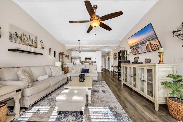 living area featuring arched walkways, dark wood finished floors, and ceiling fan with notable chandelier